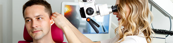 Doctor operating a machine during an ear exam.