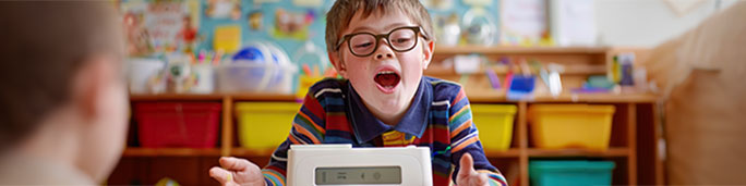 A boy with glasses looks intently at a communication device.